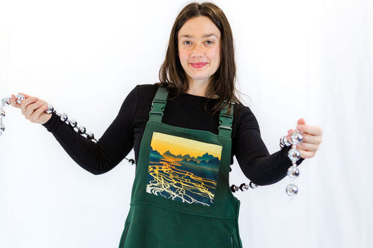 Braided River fleece overalls with wide bib and front graphic panel on dark green fabric