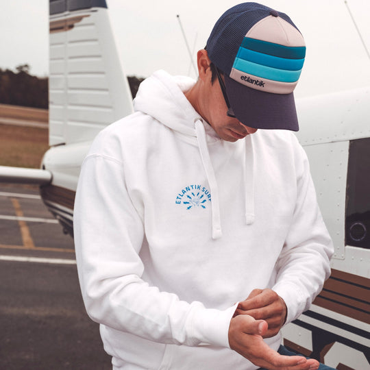 Swell Cap Blue on person: navy trucker cap with light-blue stripe band on front.