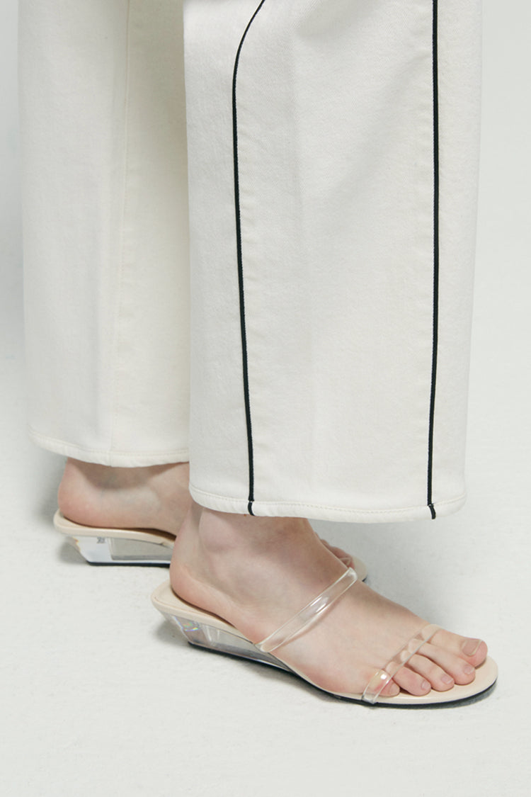 Hems close-up: white ankle jeans with dark contrast vertical seam and straight cuff