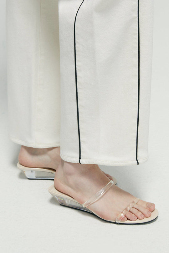 Hems close-up: white ankle jeans with dark contrast vertical seam and straight cuff