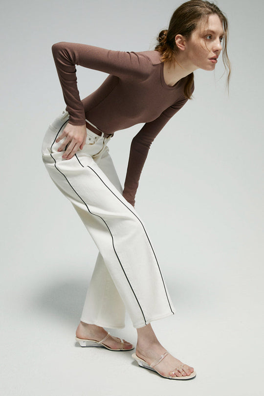 White ankle jeans with dark contrast piping along side seam and cuffed wide leg