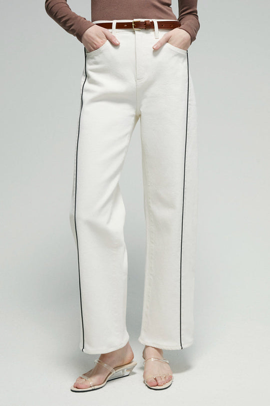 Close-up of white ankle jeans legs with dark contrast side panel stitching