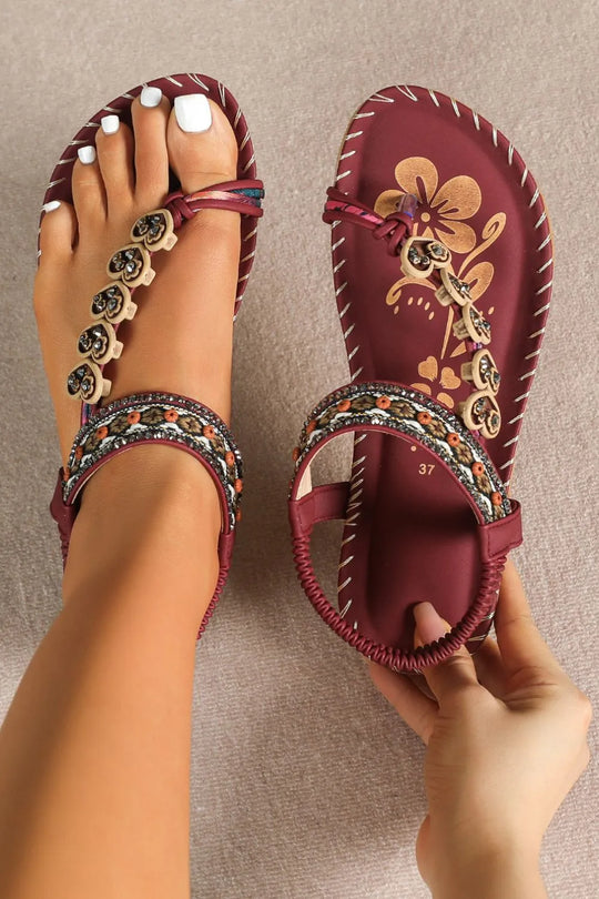 Deep red toe-loop flat sandals with floral print, beaded trim, and ankle bracelet