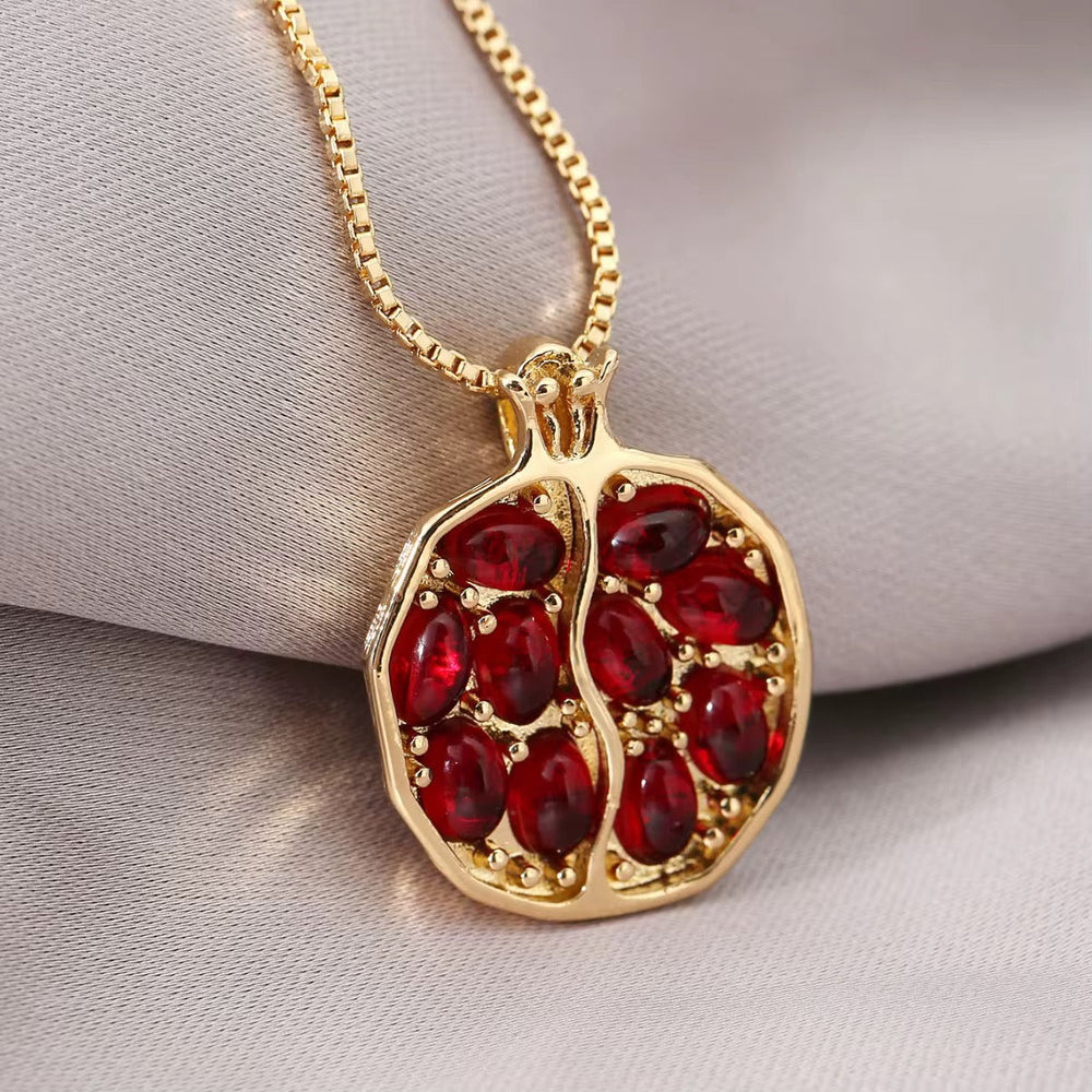 Gold-tone chain necklace with oval pomegranate pendant and red stone-filled design