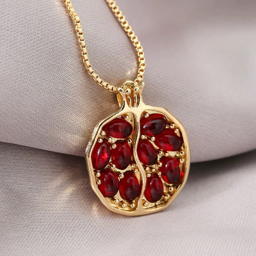 Gold-tone chain necklace with oval pomegranate pendant and red stone-filled design