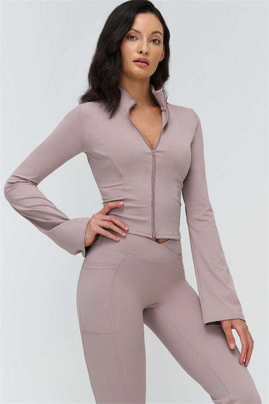 Mauve two-piece set: high-collar zip jacket and flared leggings, hands on hips