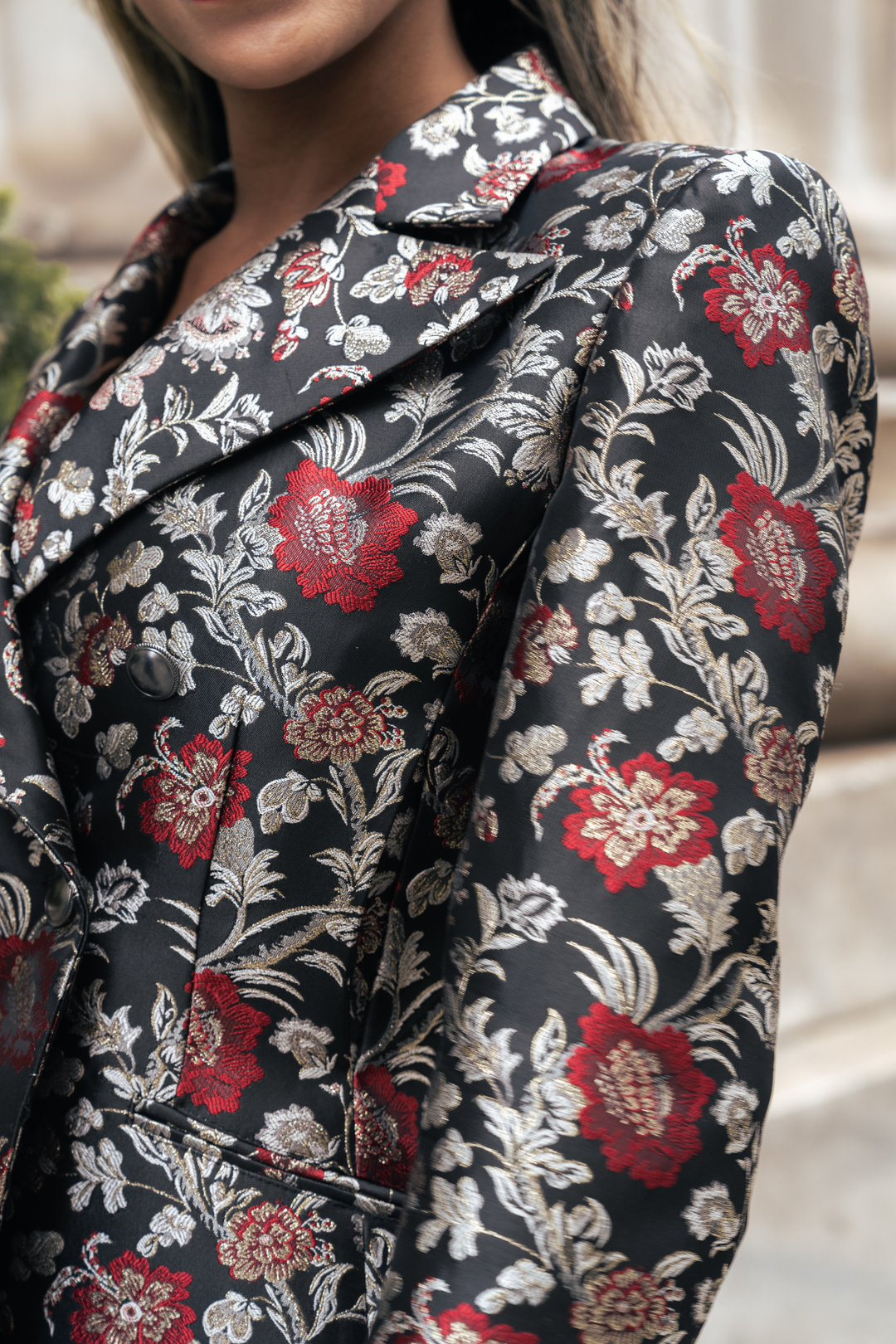 Nahaufnahme: Krimére Blazer Stoff mit rotem und beigem Blumenmuster auf dunklem Grund