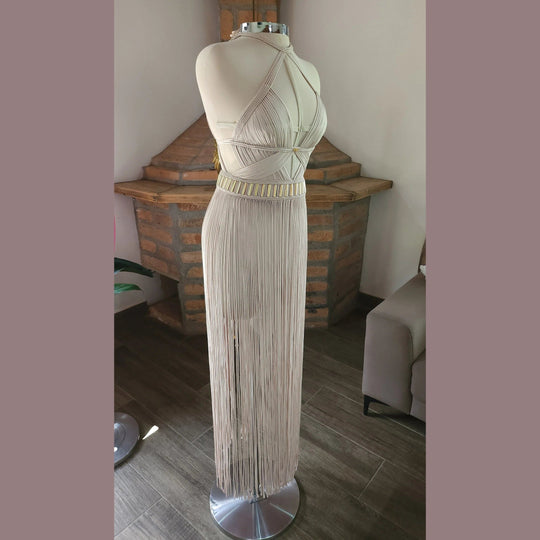 Ivory Selene maxi dress on mannequin: open-back crisscross straps, gold-accent waist, fringe