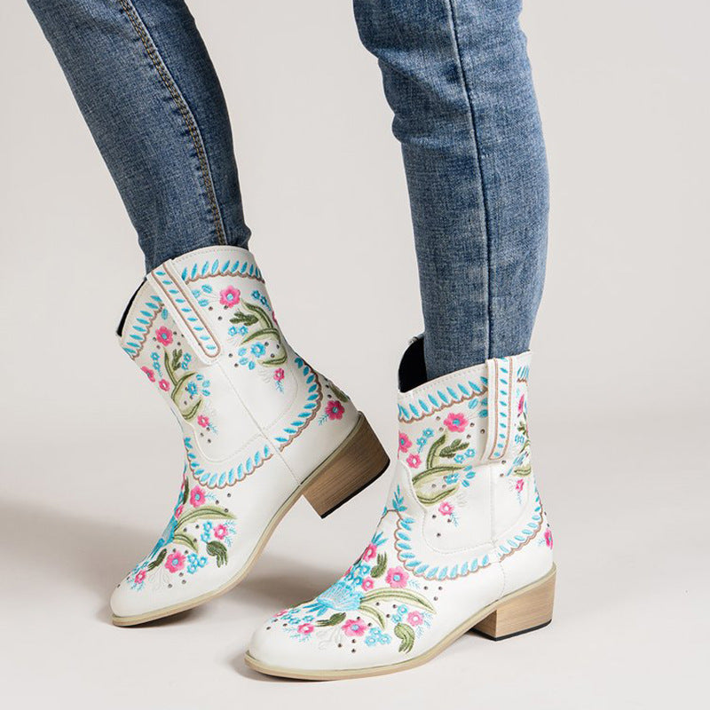 White mid-calf western boots with floral embroidery, blue trim, and low block heel