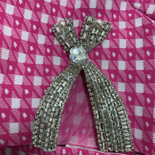 Rhinestone bow appliqué on pink knit fabric, silver-toned beaded details
