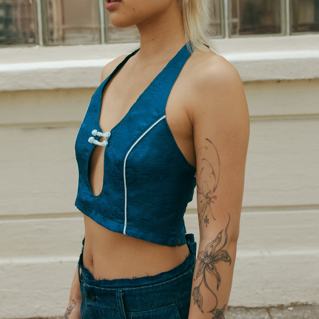 Forest blue sleeveless crop top, side view with front cutout and white piping