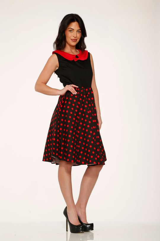 Black sleeveless swing dress with red polka dot skirt and red collar, side view