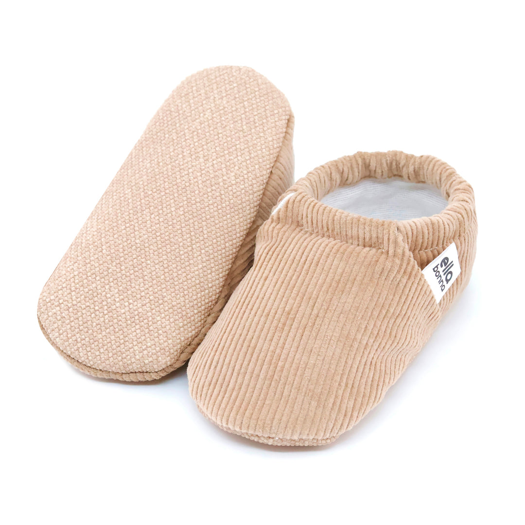 Beige soft moccasin slipper with textured fabric and heel tab, one shoe shown