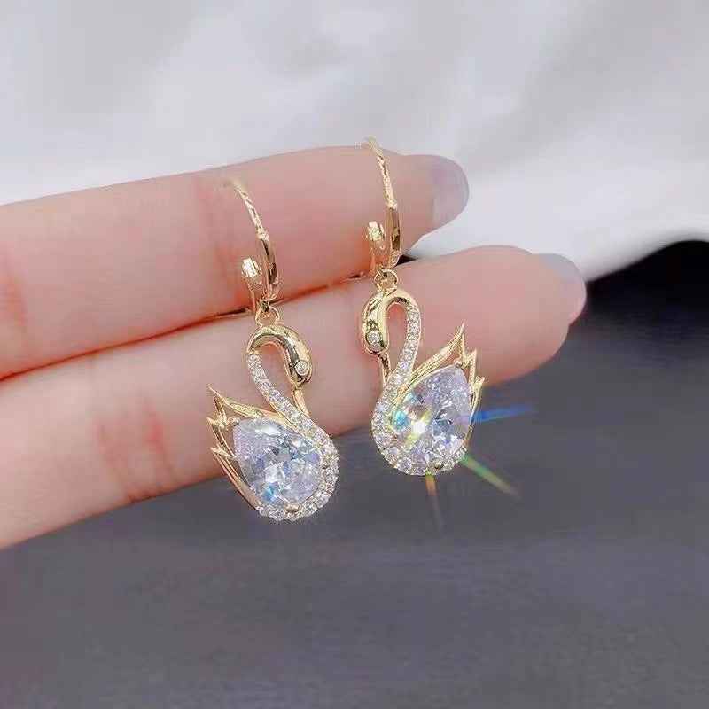 Gold-tone swan drop earrings with clear rhinestone wings and teardrop stones.