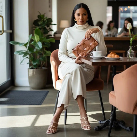 THE ZENOBIA WOVEN CLUTCH in camel-brown woven pattern, held by top handle