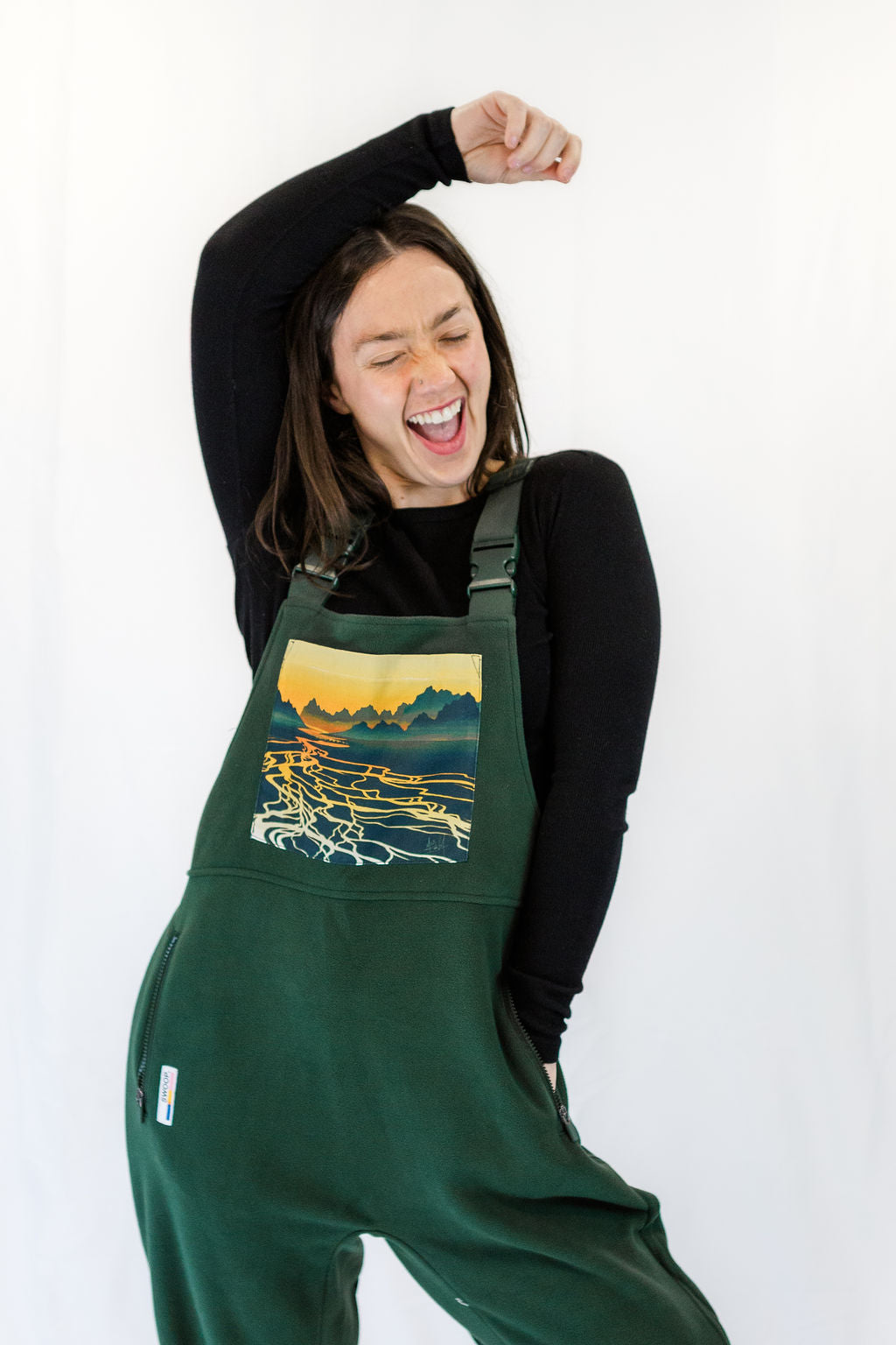 Dark green braided river fleece overalls with chest pocket featuring landscape river graphic