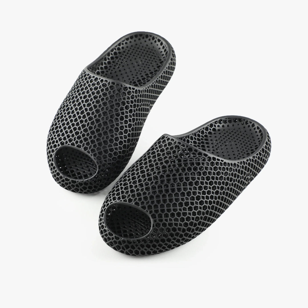 Black 3D-printed slippers, top and bottom views showing circular ventilation openings