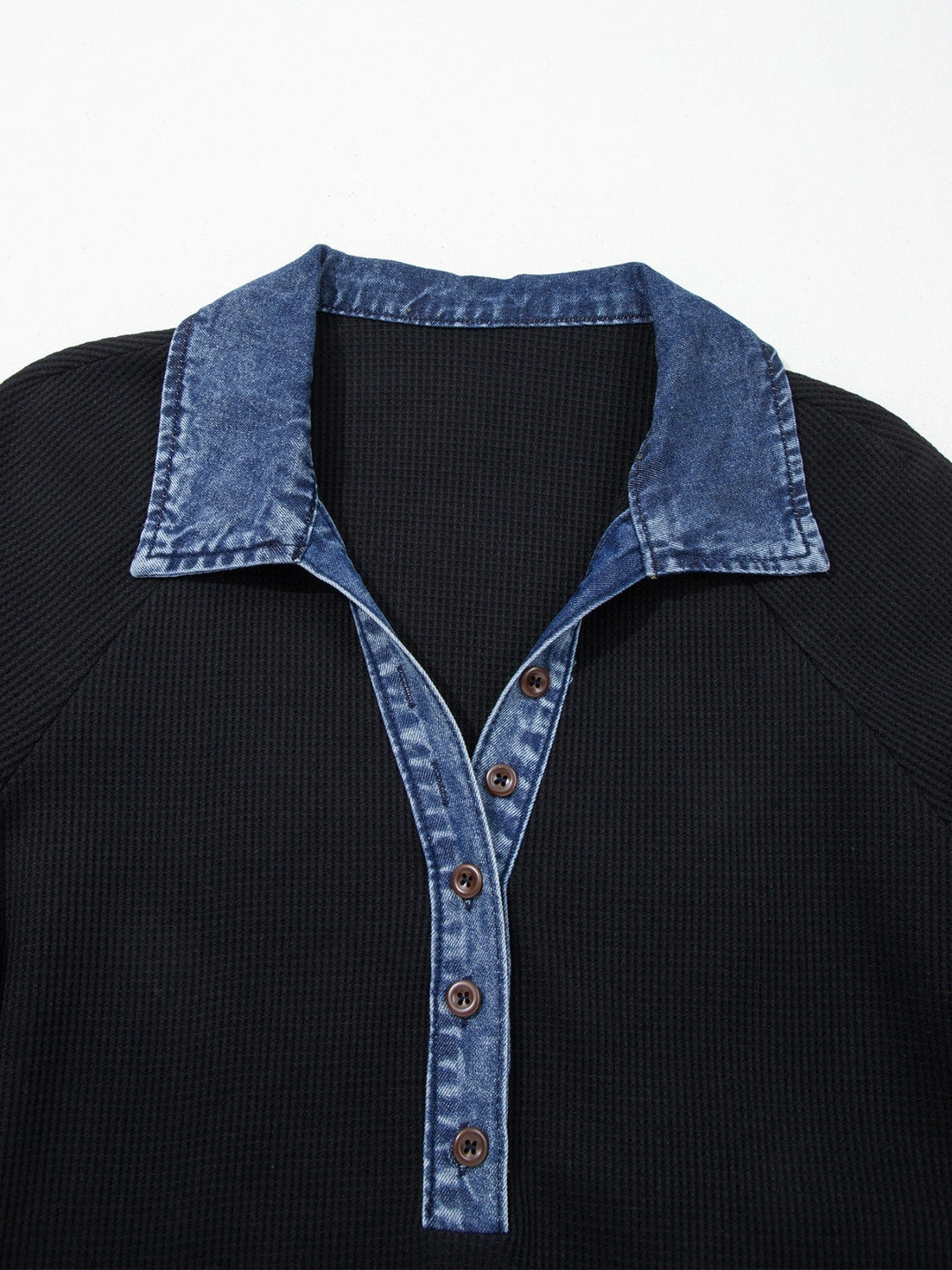 Close-up: black top with denim V placket, brown buttons and collar