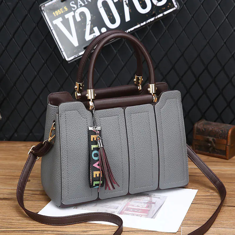 Grey fashion shoulder tote with brown handles, gold hardware, and long shoulder strap, tassel charm