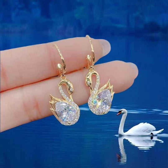 Gold-tone swan drop earrings with clear rhinestone wings and teardrop centers.