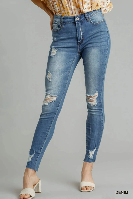 Medium wash high-waist skinny jeans with distressed patches and raw hem cuffs