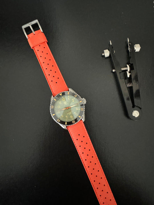 Tropic Bands watch with orange-red perforated strap and silver buckle, green dial