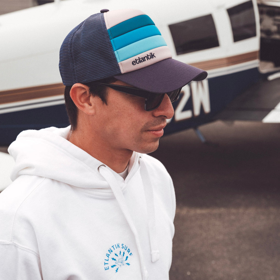 Swell Cap Blue on person: navy mesh cap with light-blue stripes and logo patch.