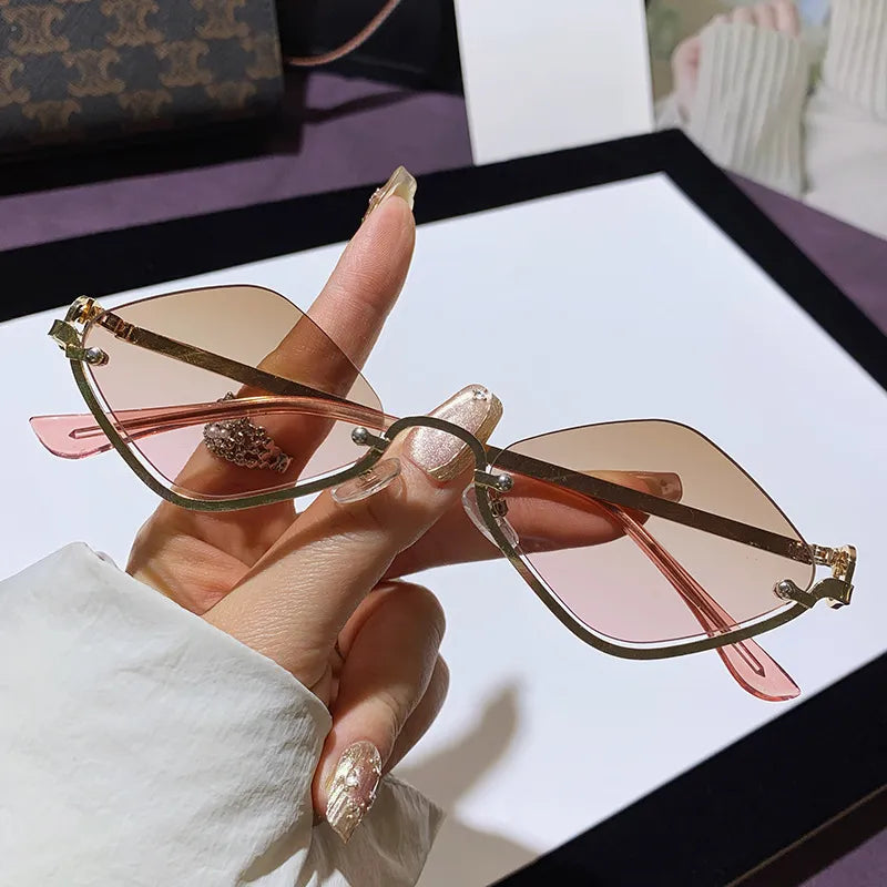 Hand hält Cat-Eye Sonnenbrille, goldfarbener Rahmen, rosafarbene getönte Gläser