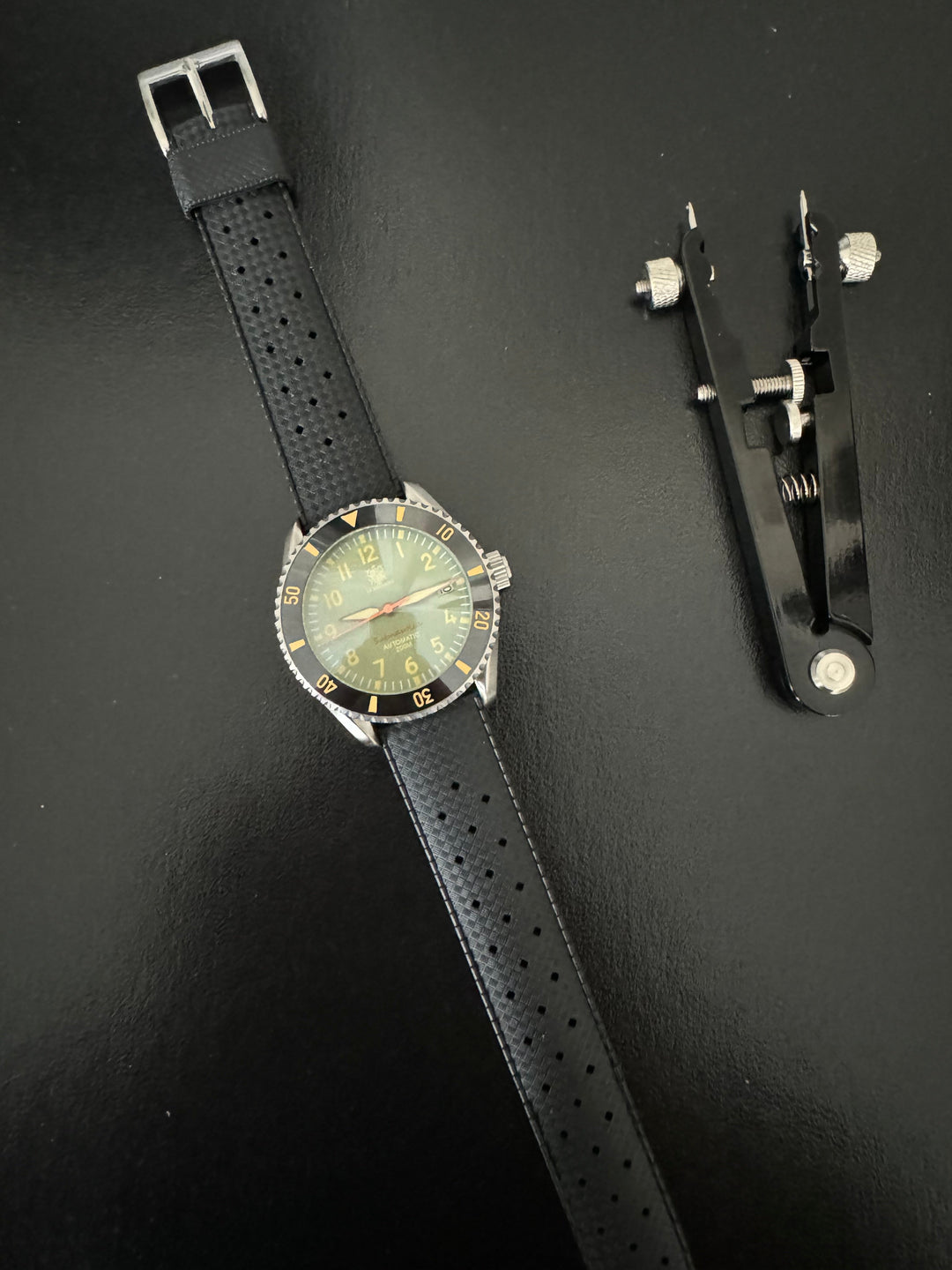 Tropic Bands watch with black perforated strap and silver buckle, light green dial
