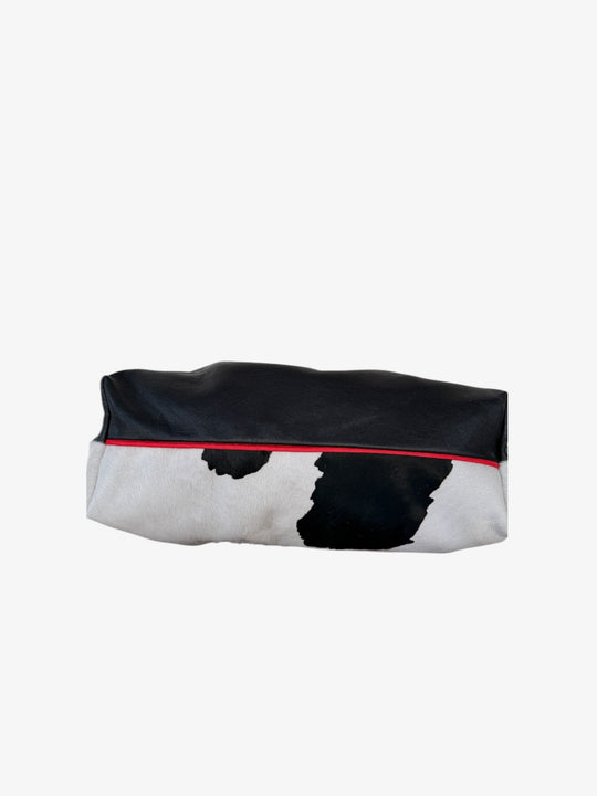 Cow-print bag with black top, red trim along the edge