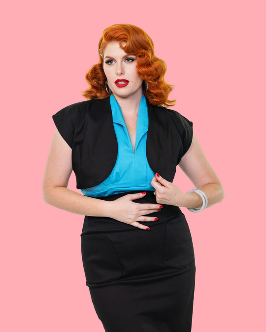 Close-up of turquoise V-neck top, open black bolero sleeves, and black pencil skirt