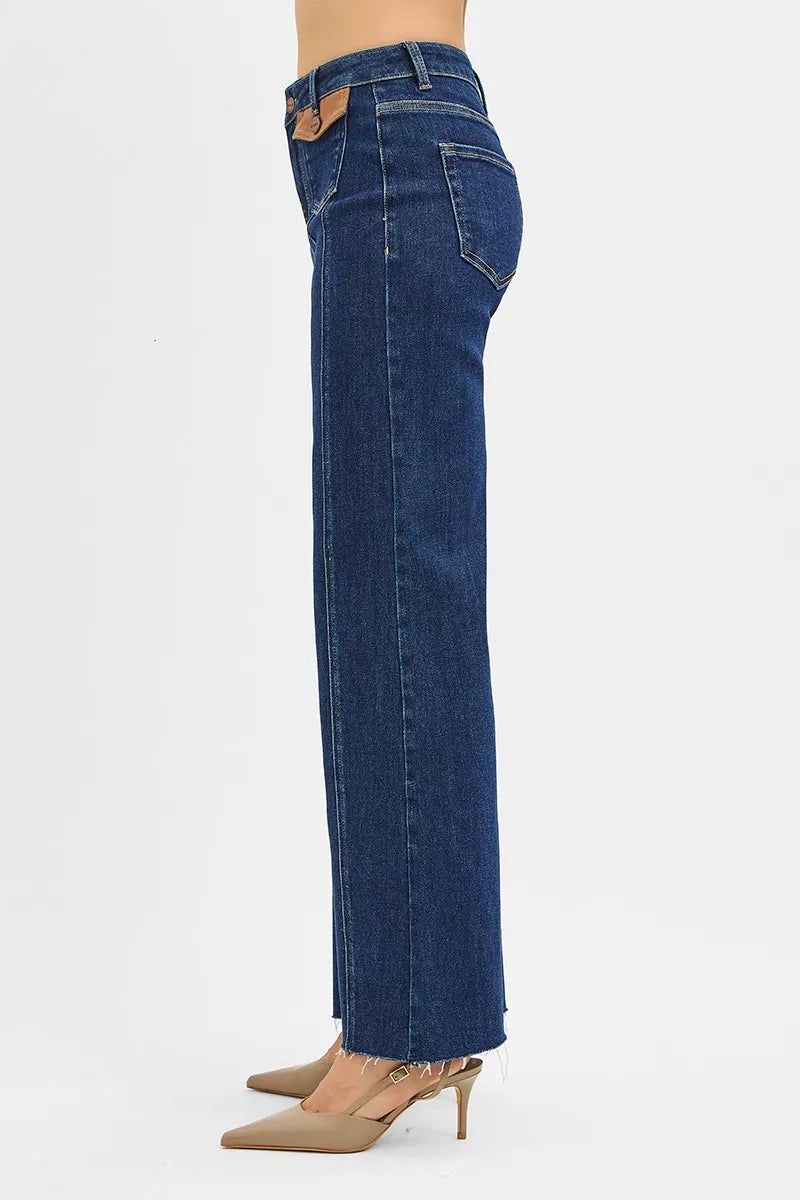 Dark wide-flare jeans side view with leather-look pocket tab and stitched seams