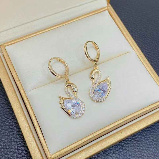 Gold-tone swan drop earrings with clear rhinestone teardrop stones in display.
