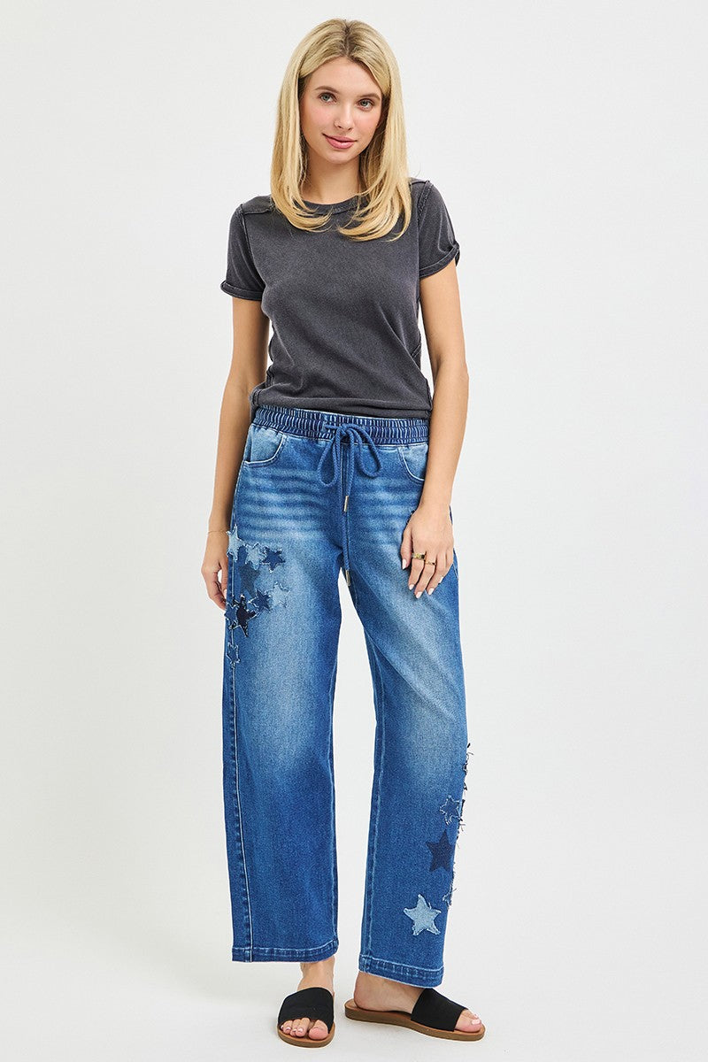 Elastic-waist cropped barrel jeans in dark denim with star patches on one leg