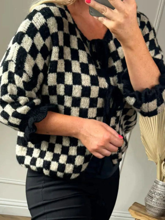 Black-and-cream checkered tie-front knit cardigan, detail view of ruffled cuff and neckline ties.