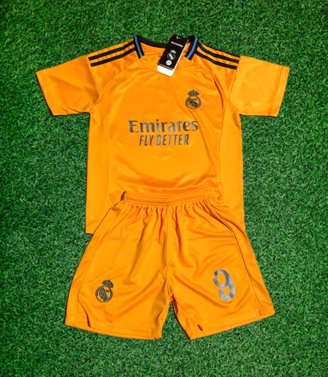 Orange Real Madrid-style kids kit with Emirates Fly Better text and number 9