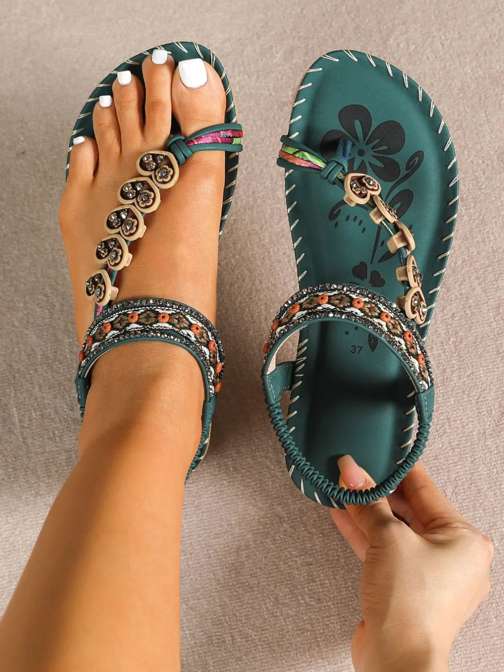 Dark green toe-loop flat sandals with stitched floral pattern and beaded trim