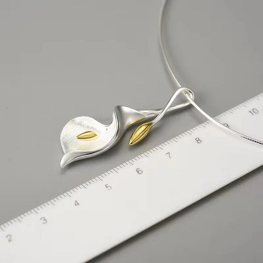 Silver calla lily necklace pendant with gold center, shown with a measurement ruler