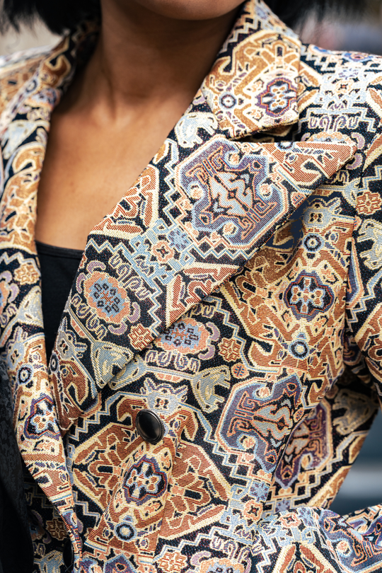 Detalle del blazer: solapa cruzada y botón oscuro con estampado naranja y azul