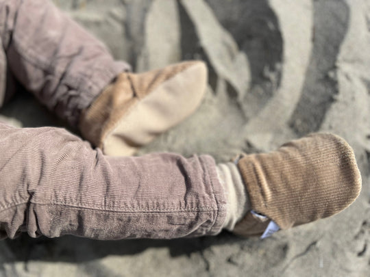 Beige corduroy baby moccasin shoes on a baby’s foot