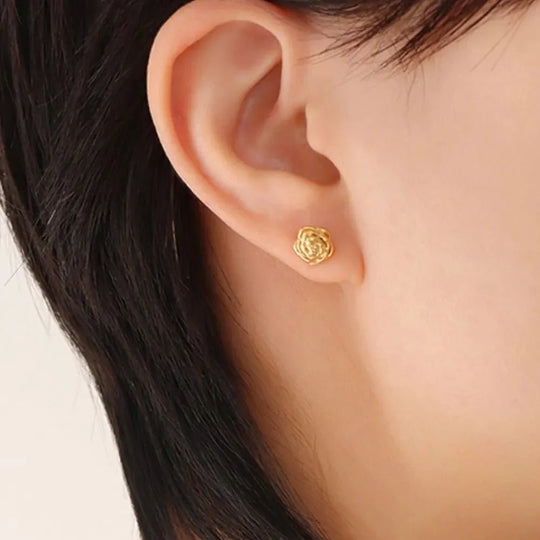 Gold petal stud earrings, worn: textured circular design on ear lobe