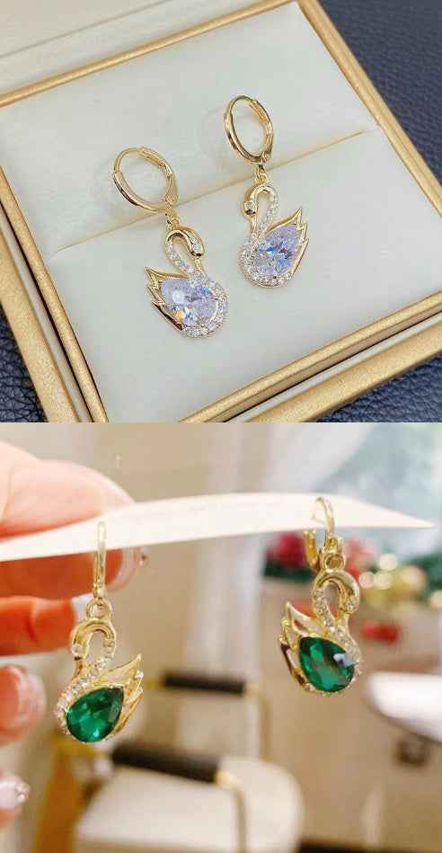 Gold-tone swan earrings: clear and green rhinestone teardrop centers on display.