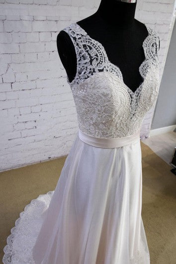 Ivory lace V-neck bodice with scalloped detailing and satin waist sash, full skirt