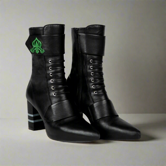 Black ankle boots front view with green fleur-de-lis emblem and lace-up eyelets