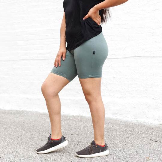 Teal (peacock) biker shorts, mid-thigh length, small logo label on back.