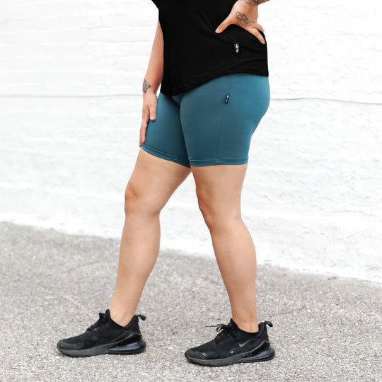 Teal biker shorts with small back logo, fitted mid-thigh length.
