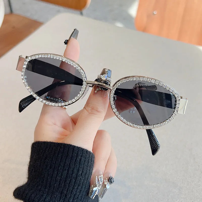 Oval rhinestone sunglasses with silver-tone sparkle frame, dark lenses, and pointed tips