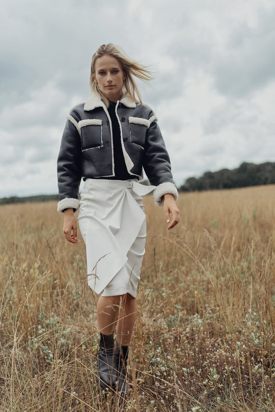 Black sherpa-lined leather jacket with cream trim at collar, cuffs, and hem