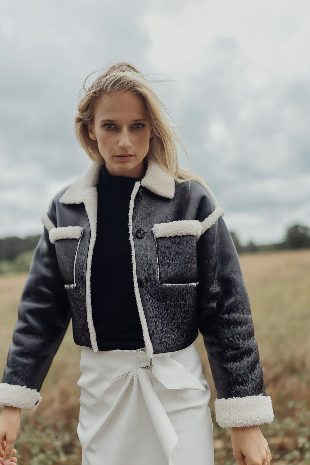Black leather jacket with cream sherpa trim, buttoned chest pockets and placket