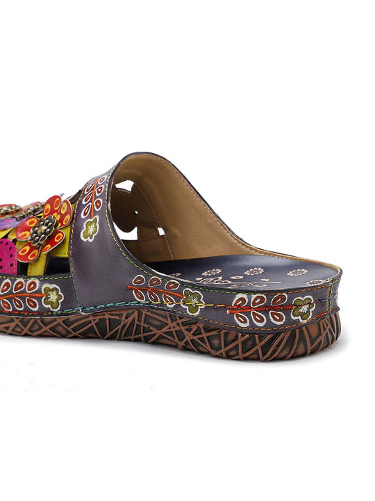 Close-up of floral slipper heel and strap, dark base with colorful stitched motifs
